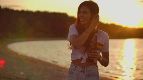 The-girl-laughs-and-touches-her-hair-at-sunset-on-the-beach.-This-is-perfect-summer-evening-with-beer-and-friends.